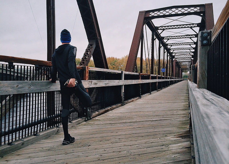 Man stretching on wooden bridge railing