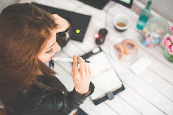 Young woman thinking with pen at white desk