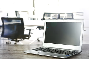 Silver laptop on wooden desk in bright modern office