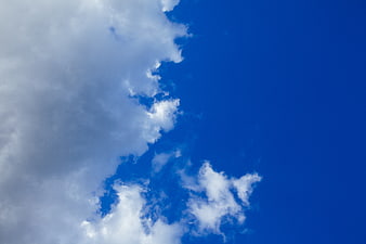 Fluffy white clouds against a deep blue sky background