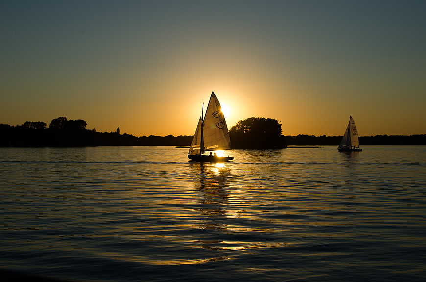 Sailboats Silhouetted Against Golden Sunset on Calm Water