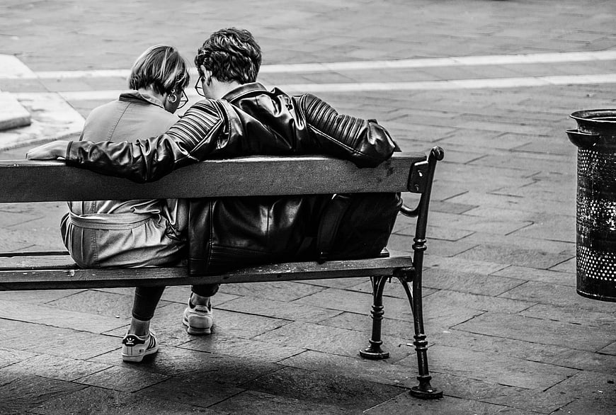Couple sitting on a bench in black and white
