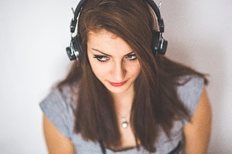Young woman with headphones looking down listening to music