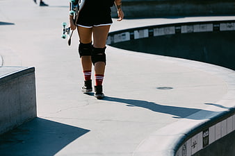 Skateboarder Walking in Concrete Skatepark