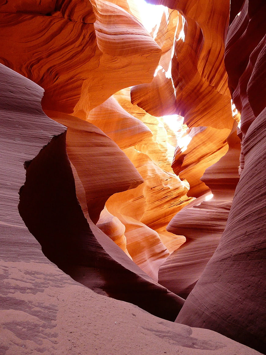 Sunlight streaming through swirling red sandstone canyon walls