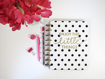 Flat lay of polka dot notebook with pink flowers and stationery