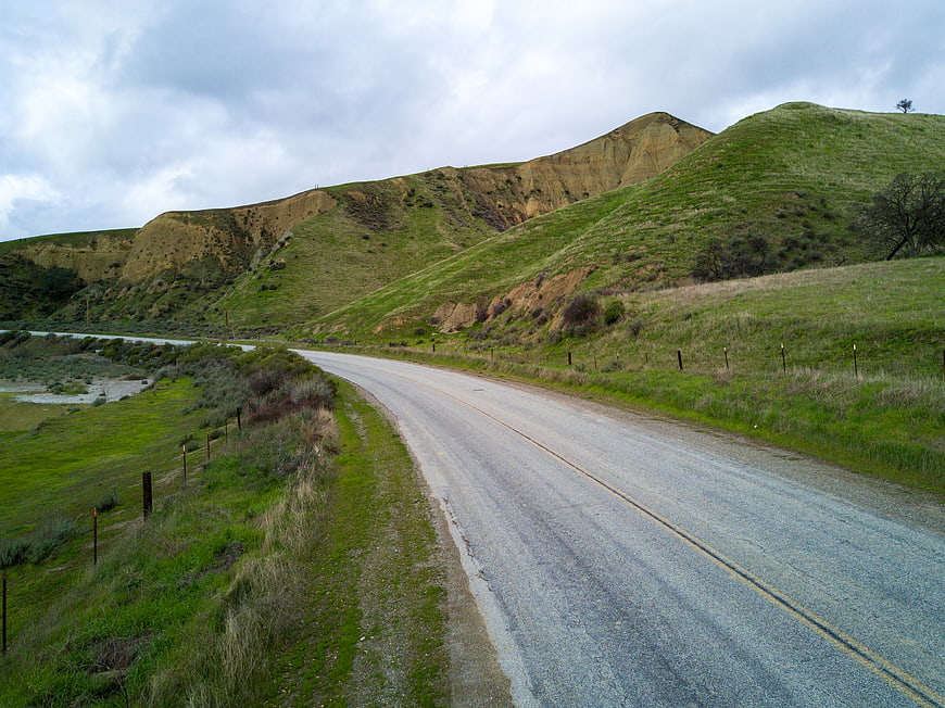 Winding Country Road Through Green Hills and Cliffs