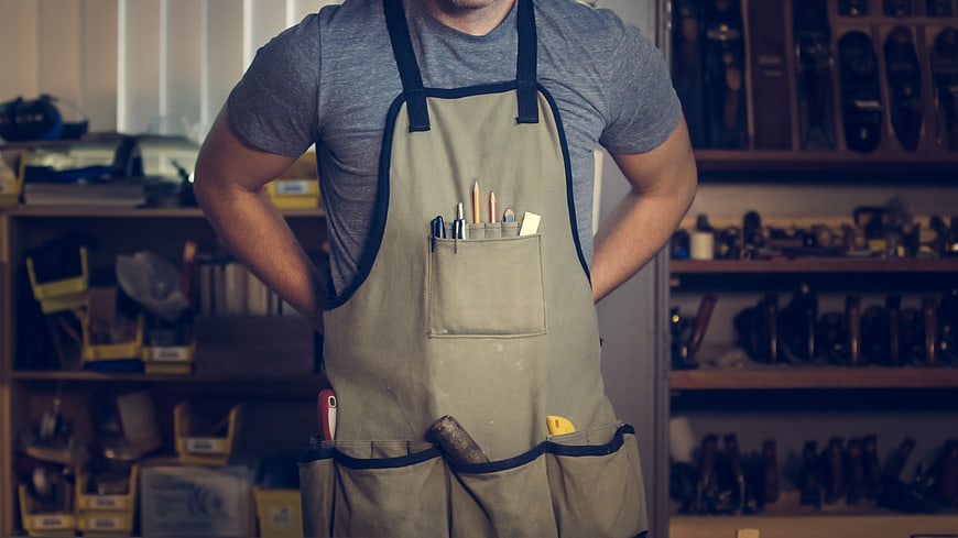 Carpenter in Apron with Tools in Workshop