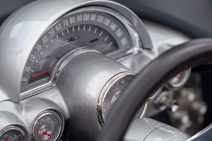 Close-up of vintage silver car dashboard with speedometer and gauges