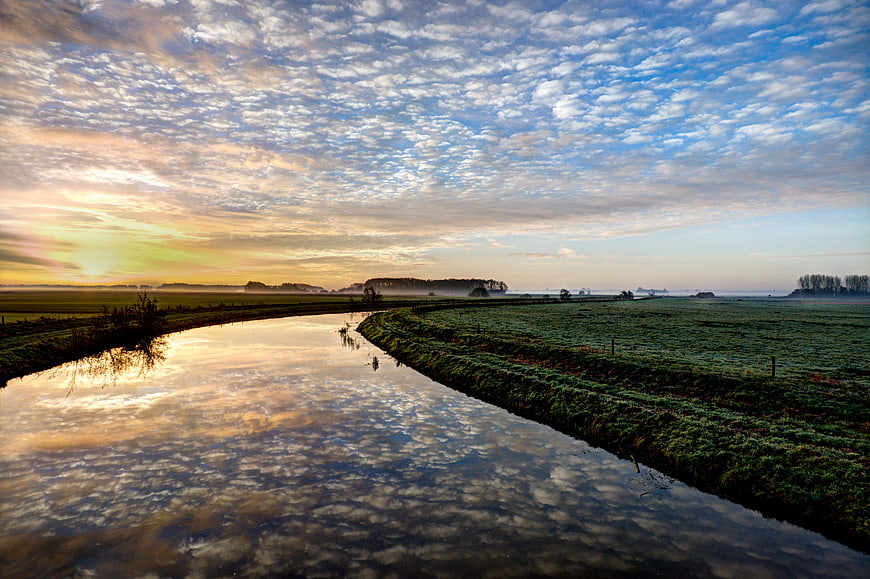 Serene River Sunrise with Cloud Reflections in Frosty Meadow