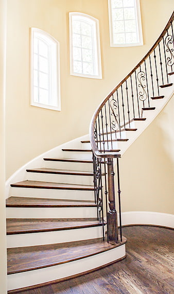 Elegant curved wooden staircase with wrought iron railing