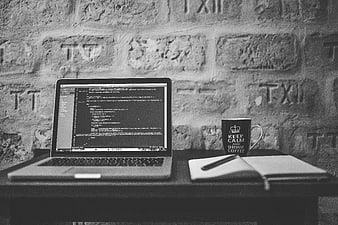 Black and white laptop workspace with code and coffee mug