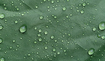 Macro shot of water droplets on green waterproof fabric texture