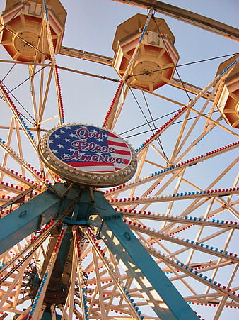 Low angle view of vintage Ferris wheel with patriotic sign