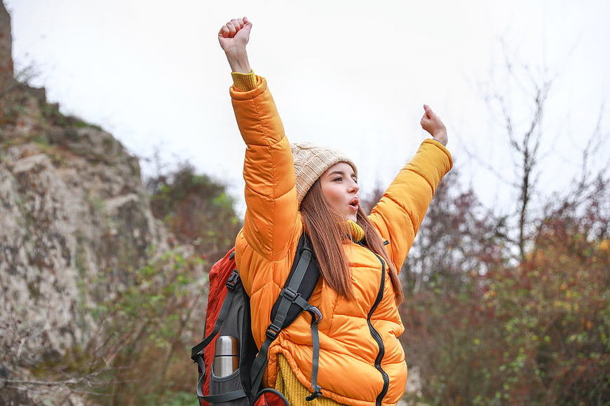 Happy female hiker celebrating in autumn forest