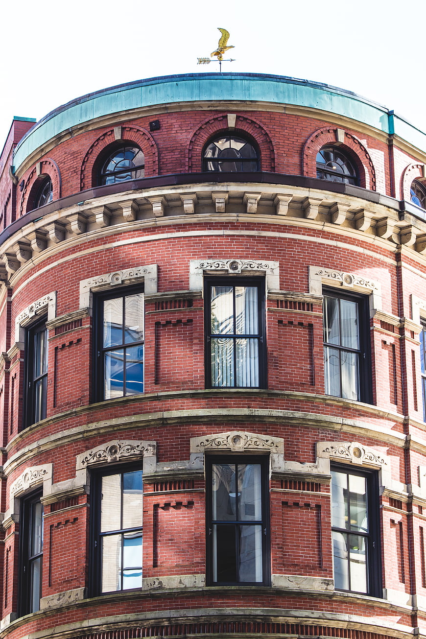 Red Brick Corner Building with Ornate Windows and Weathervane