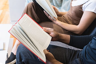Close-up of Couple Reading Books Together on Sofa