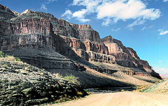 Dirt road winding through red rock canyon cliffs under blue sky