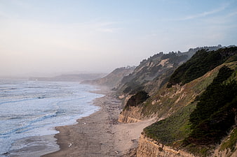 Misty coastal landscape with sandy beach and cliffs