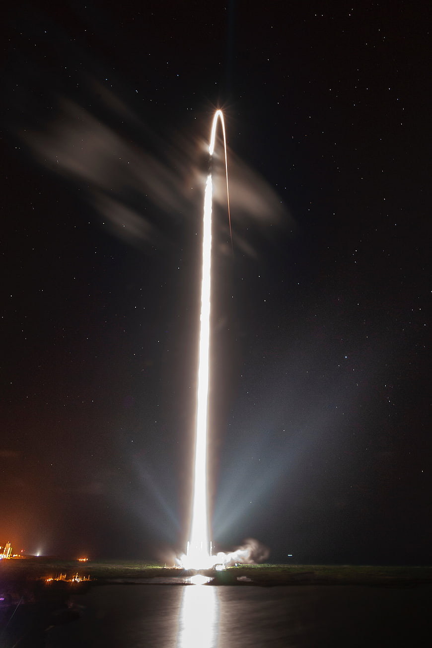 Night rocket launch with bright trail and starry sky