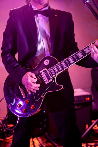 Musician playing electric guitar on stage in tuxedo