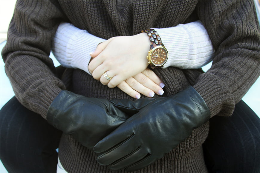 Close-up of woman's hands with watch and leather gloves
