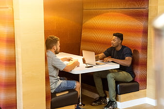Two men collaborating in a modern office booth