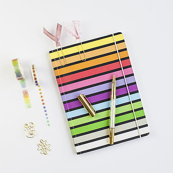 Colorful striped notebook with stationery flat lay
