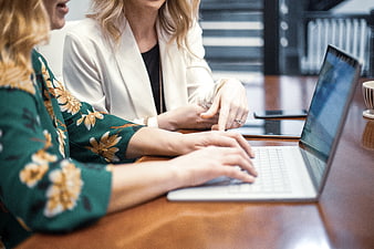 Two female colleagues collaborating on a laptop in a modern office