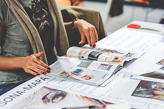 Person working on persona map with magazines and papers