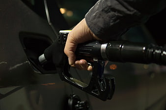 Close-up of hand holding gas pump nozzle at night