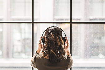 Woman Listening to Music with Headphones by Window