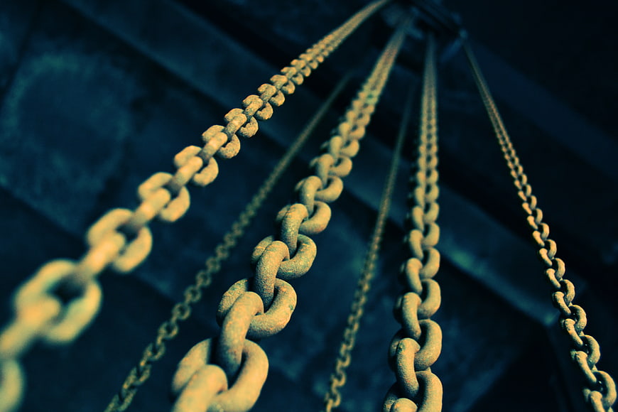 Rusty metal chains hanging against dark blue background