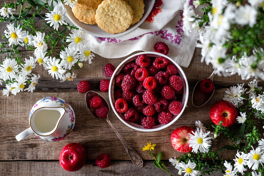 Top View of Raspberries, Apples, and Daisies on Wooden Table