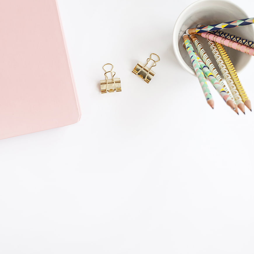 Minimalist pastel stationery flat lay with gold clips and pencils