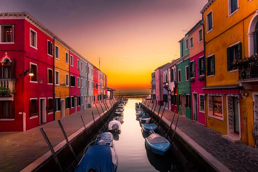 Colorful canal houses in Burano at sunset with boats