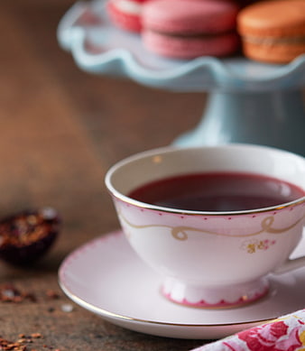 Pink Tea Cup with Macarons on Wooden Table