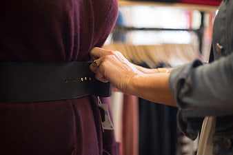 Woman adjusting belt on purple dress in clothing store