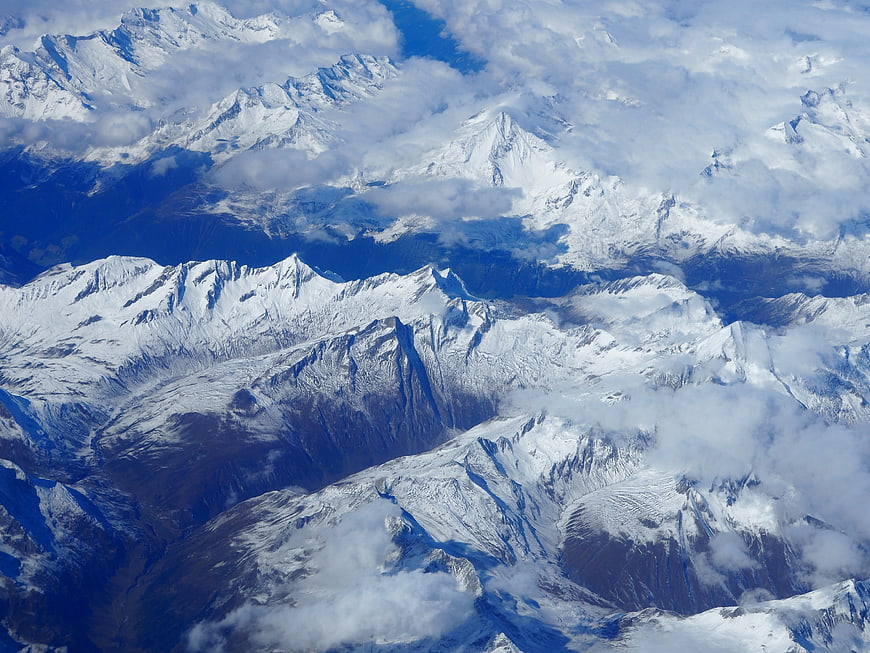 Aerial View of Snow-Covered Mountain Peaks and Clouds