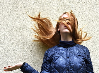 Woman with Windblown Red Hair Against Textured Wall