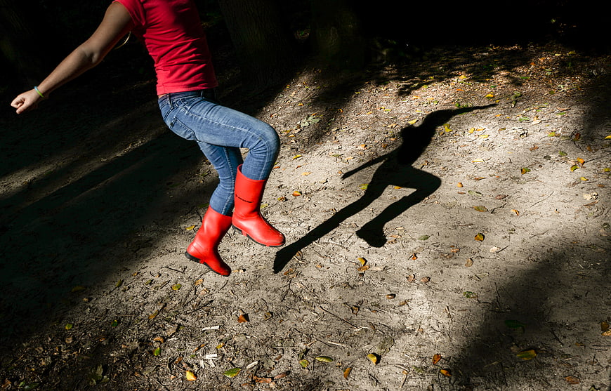 Woman Jumping in Red Boots in Forest