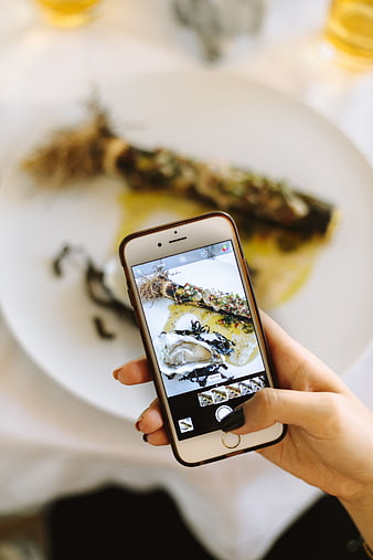 Woman taking photo of gourmet seafood dish with smartphone