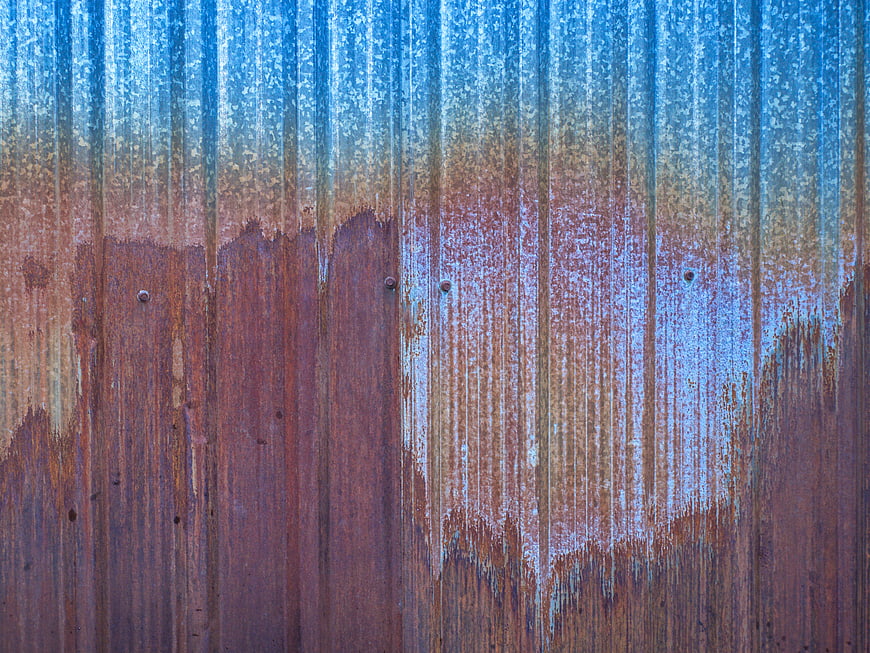 Rusted corrugated metal texture with blue and orange patina