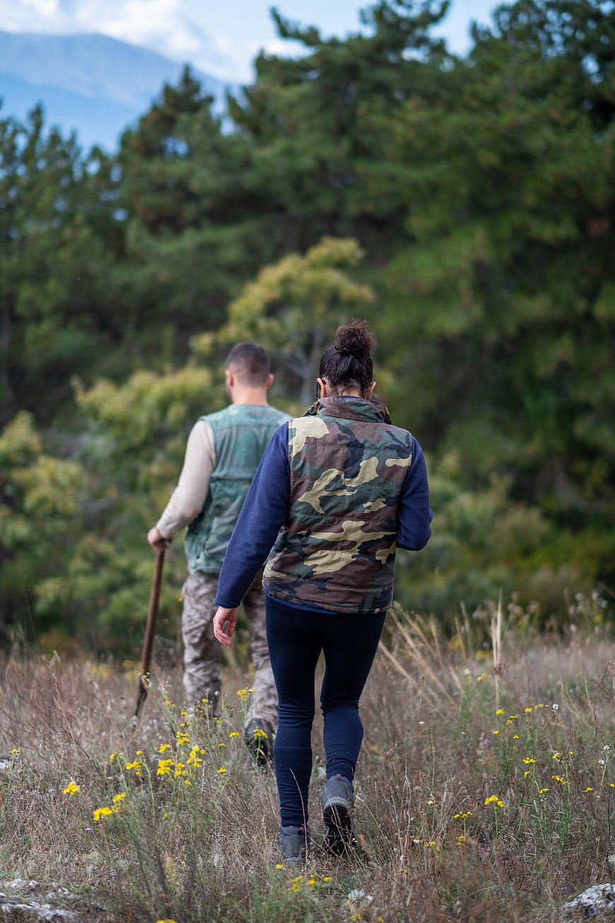 Couple hiking through wildflower field with forest background