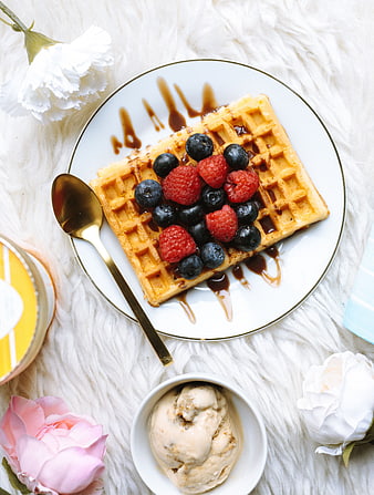 Overhead view of waffle with berries and ice cream on white fur