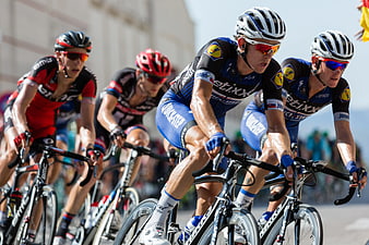 Professional Cyclists Racing on Road in Blue and Red Kits