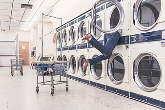 Person hiding inside laundry machine at laundromat