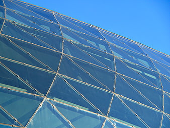 Modern glass building facade with geometric pattern against blue sky