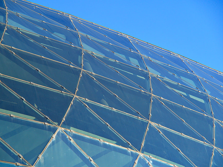 Modern glass building facade with geometric pattern against blue sky