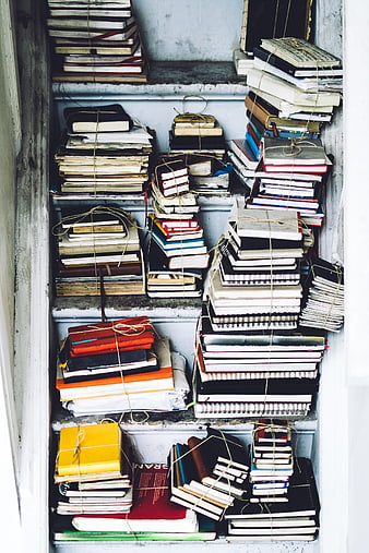 Stacks of vintage notebooks and books tied with twine on shelves
